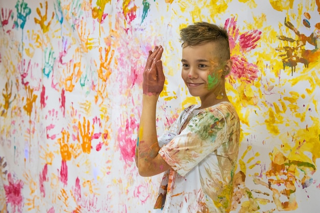 Foto retrato de um menino fofo e feliz pintando e se divertindo