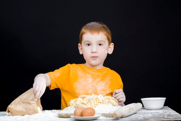 Retrato de um menino na cozinha, ajudando a cozinhar