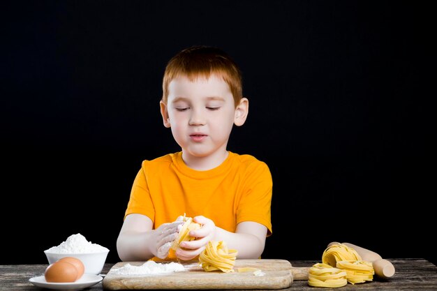 Retrato de um menino na cozinha enquanto ajudava a cozinhar, um menino com cabelo ruivo e belos traços faciais, ajudando uma criança na cozinha