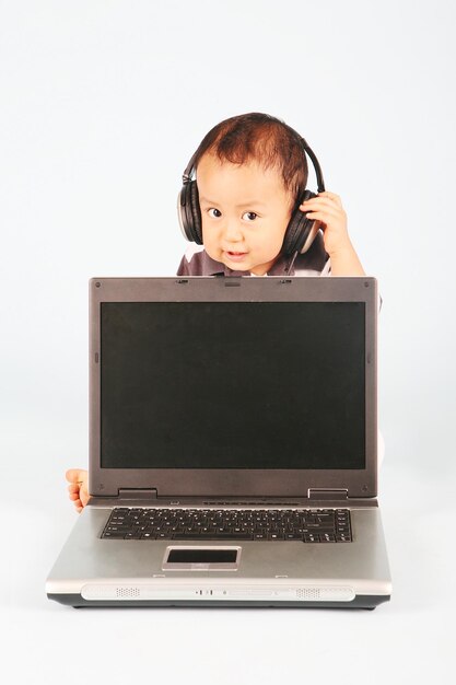 Foto retrato de um menino ouvindo música com um laptop contra um fundo branco