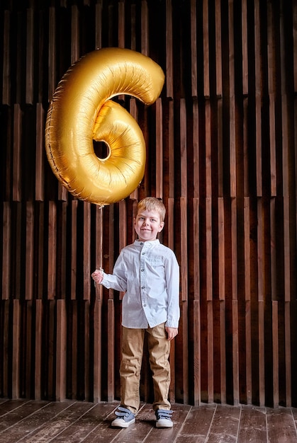 Foto retrato de um menino segurando um balão de número 6