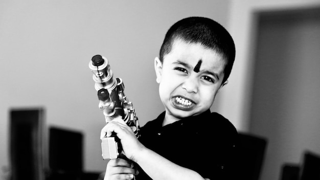 Retrato de um menino segurando uma arma de brinquedo