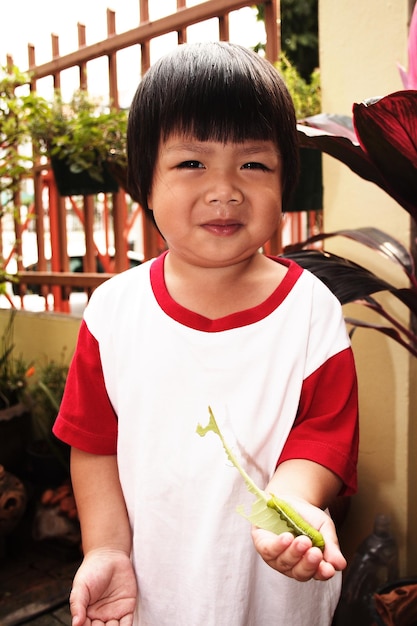 Foto retrato de um menino segurando uma folha com um inseto