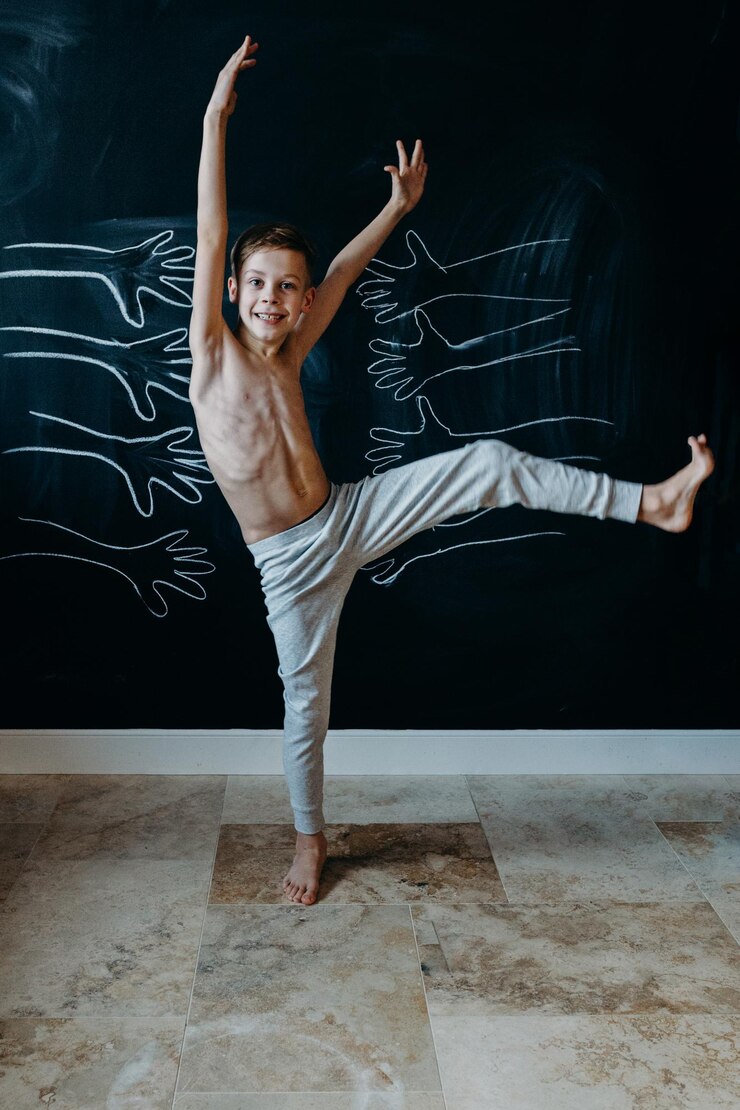 Foto retrato de um menino sem camisa dançando contra a parede