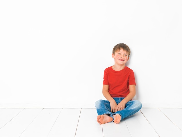 Foto retrato de um menino sentado no chão de azulejos