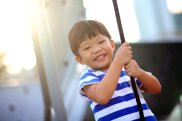 Retrato de um menino sorridente balançando no baloiço