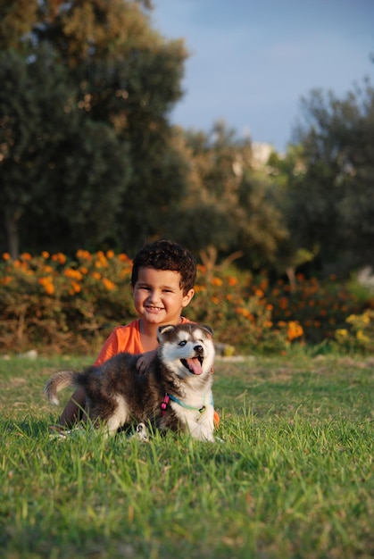 Retrato de um menino sorridente com um cão na grama