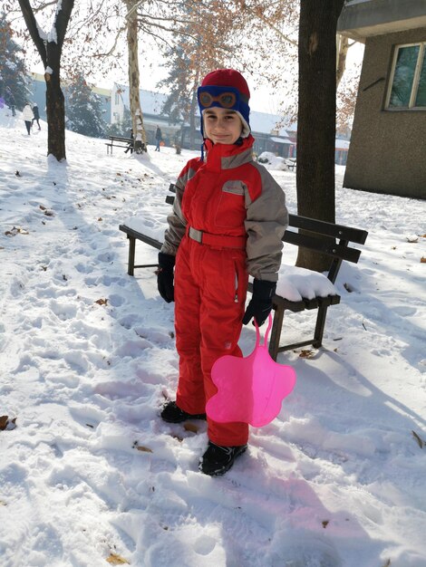 Foto retrato de um menino sorridente de pé em um campo de neve