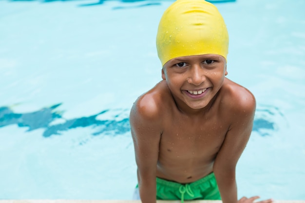 Retrato de um menino sorridente em pé na piscina