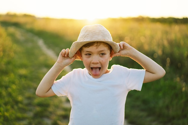 Retrato de um menino sorridente em uma camiseta branca levantando as mãos e jogando