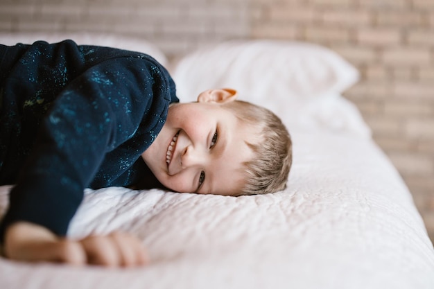 Retrato de um menino sorridente na cama em casa