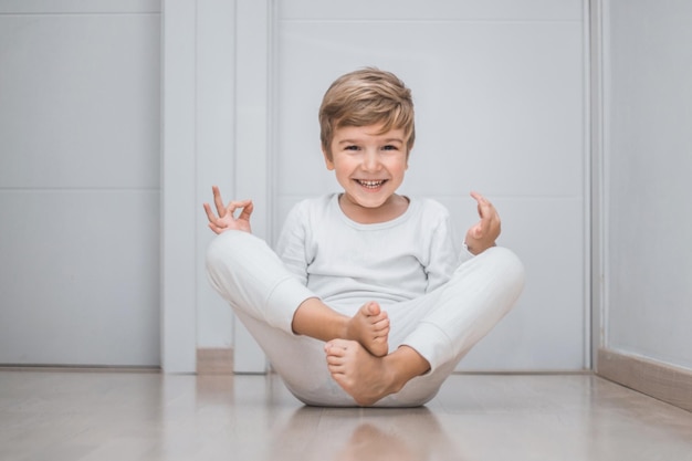 Retrato de um menino sorridente praticando ioga no chão