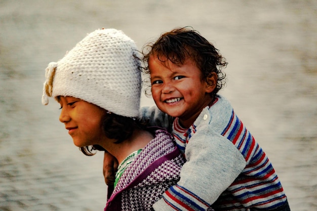 Retrato de um menino sorridente sendo empurrado pela irmã contra o mar