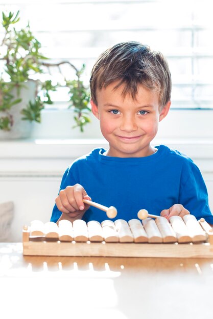 Foto retrato de um menino sorridente tocando xilofone na mesa