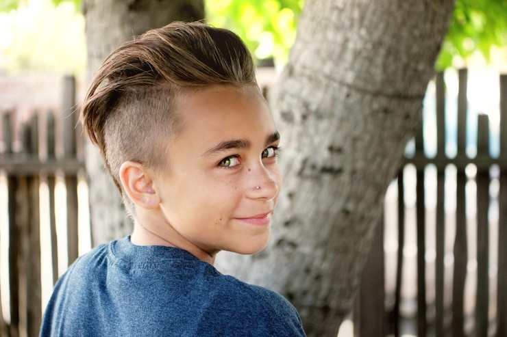 Foto retrato de um menino sorrindo contra troncos de árvores