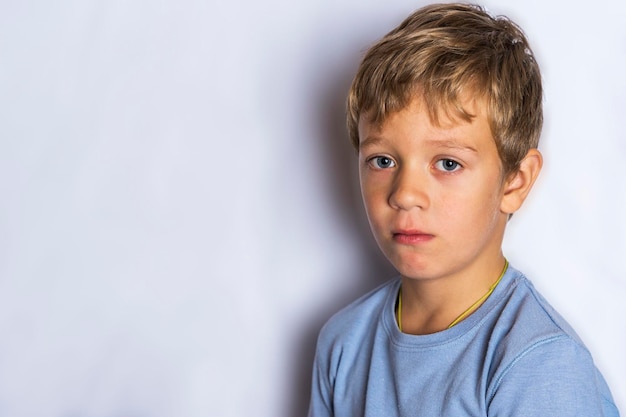 Retrato de um menino triste em um fundo branco uma criança frustrada