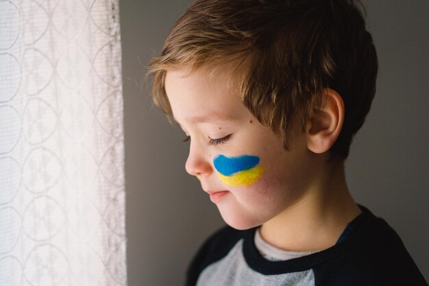 Retrato de um menino ucraniano com um rosto pintado com as cores da bandeira ucraniana