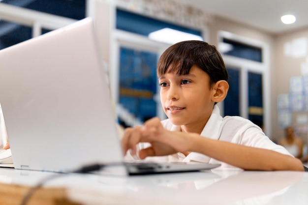 Retrato de um menino usando um dispositivo digital na sala de aula da escola