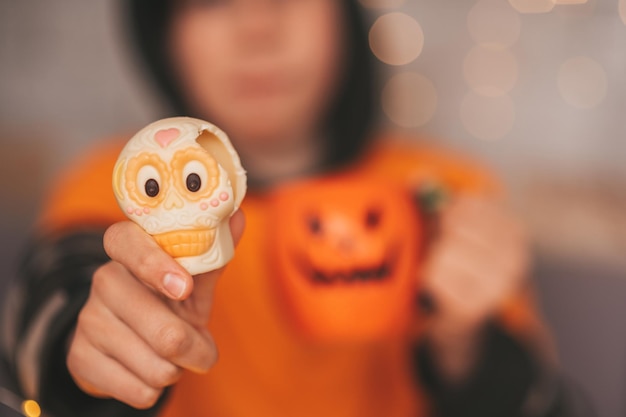 Retrato de um menino zoomer autêntico e sincero posando com uma xícara de chá e doces em casa, festa de Halloween