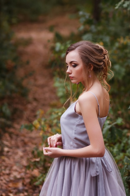 Foto retrato de um modelo de vestido roxo com um penteado bonito. fundo desfocado, efeito artístico.