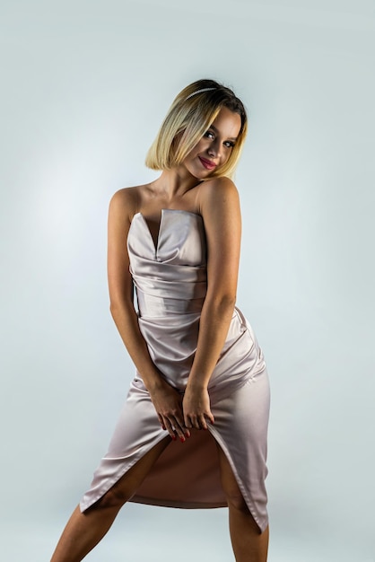 Retrato de um modelo feminino de uma menina loira em um lindo vestido de seda noturno no estúdio