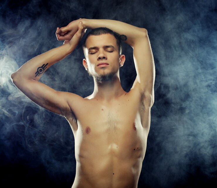 Foto retrato de um modelo masculino musculoso contra parede escura com fumaça.