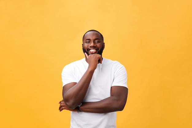 Retrato, de, um, moderno, jovem, homem preto, sorrindo, com, braços cruzaram, ligado, isolado, fundo amarelo