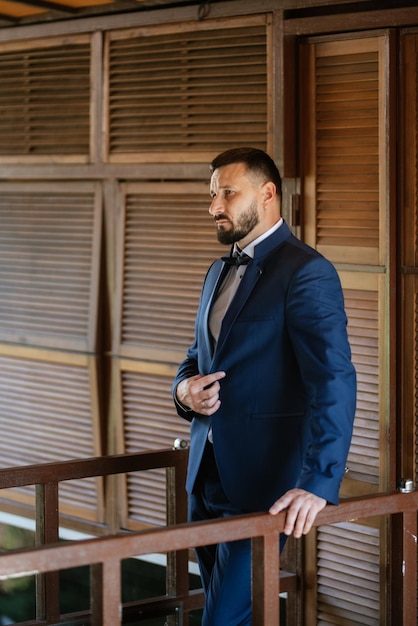 Retrato de um noivo com barba em um terno azul