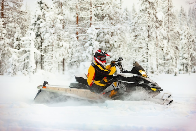 Retrato de um piloto de snowmobile em equipamento com capacete andando em uma superfície de neve ao ar livre