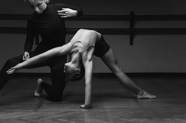 Retrato de um professor de coreografia a ajudar uma menina a posar corretamente num estúdio de dança