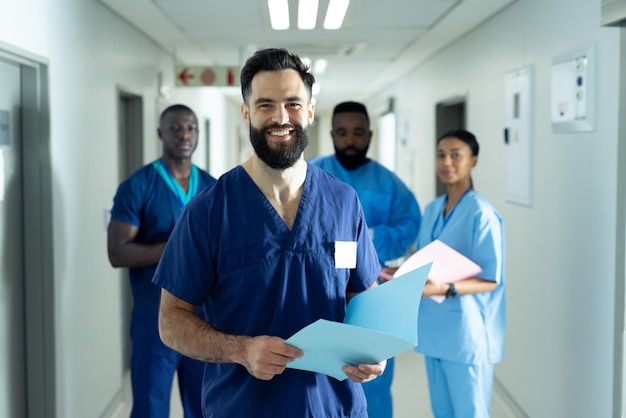 Retrato de um profissional de saúde masculino caucasiano sorridente com arquivo no movimentado corredor do hospital