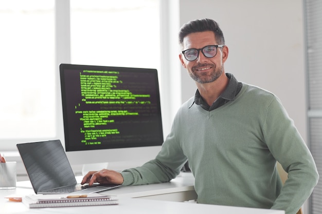 Foto retrato de um programador de computador maduro usando óculos, olhando para a frente enquanto desenvolve um novo sistema de computador