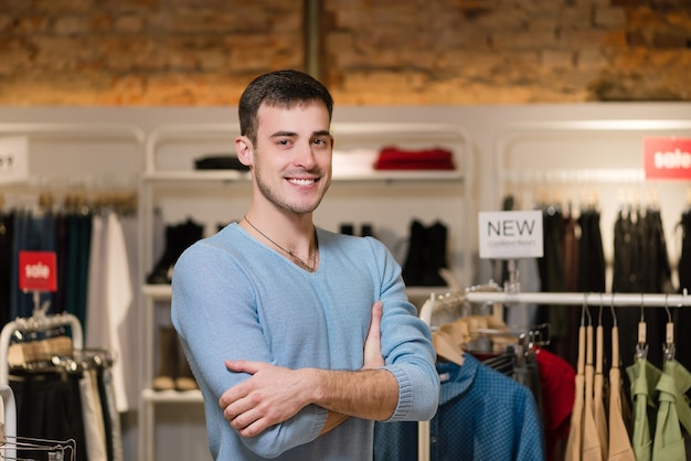 Retrato de um proprietário masculino de sucesso com os braços cruzados em uma loja de roupas