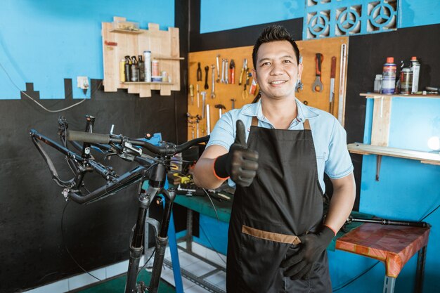 Retrato de um reparador bonito com os polegares para cima em um avental