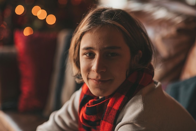 Retrato de um sincero e autêntico adolescente sorridente divertindo-se em uma loja de madeira decorada para o Natal