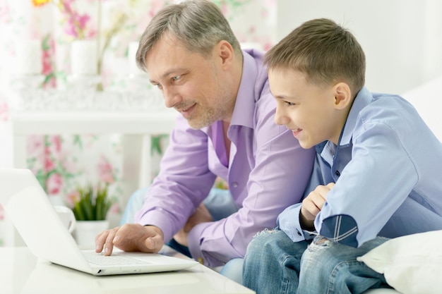 Retrato de um sorridente pai e filho usando laptop