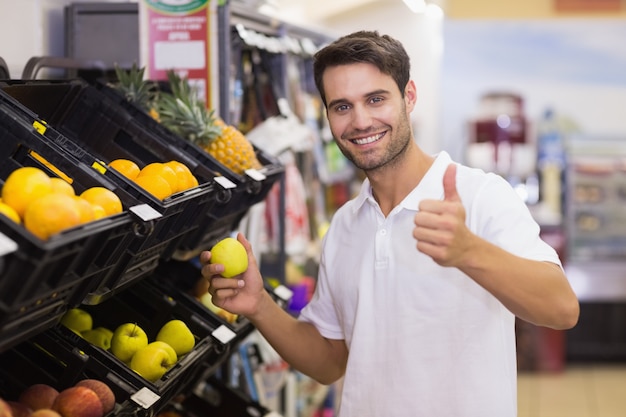 Retrato, de, um, sorrindo, homem bonito, comprando um fruto, com, polegar cima