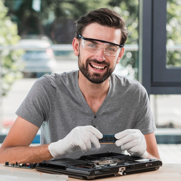 Foto retrato, de, um, sorrindo, jovem, macho, técnico, segurando, laptop, ram