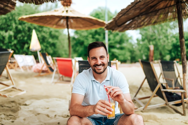 Retrato de um suco de laranja bebendo do homem ocasional na praia.