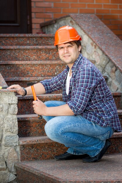 Retrato de um trabalhador da construção civil a reparar uma escada de pedra