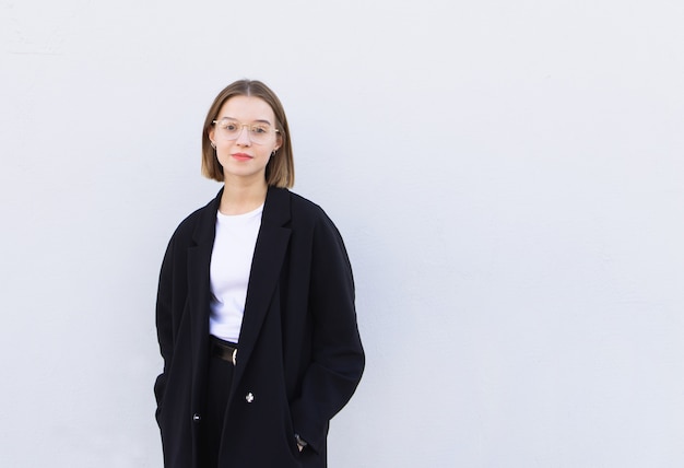 Retrato de um trabalhador de escritório feminino jovem elegante de óculos e uma jaqueta, de pé em branco