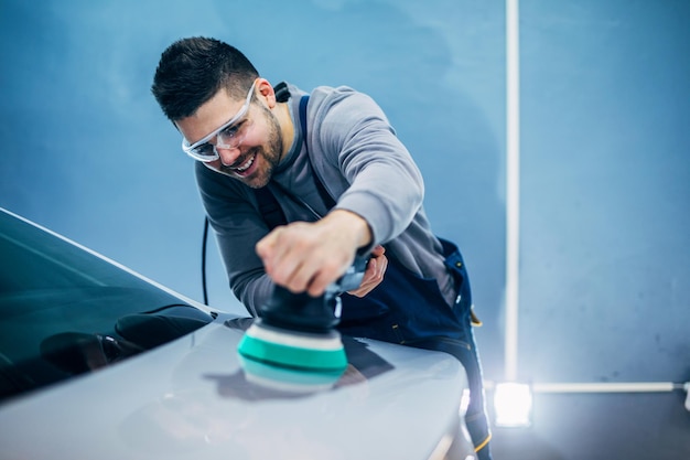 Retrato de um trabalhador sorridente desfrutando de polir um carro