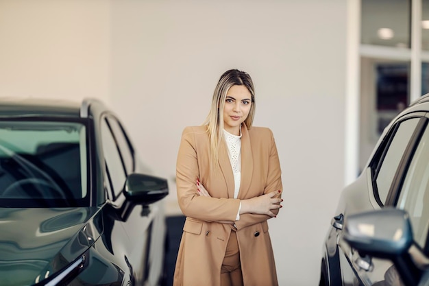 Retrato de um vendedor de carros confiante em pé no centro de concessionárias de carros e sorrindo para a câmera