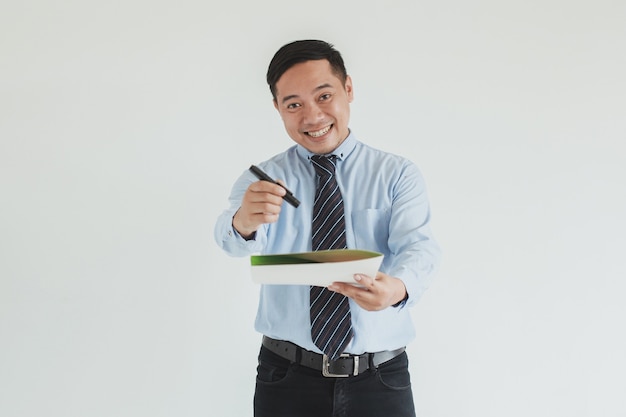 Retrato de um vendedor sorridente, vestindo camisa azul e gravata, estendendo a mão enquanto segura uma caneta e uma carta de acordo para assinar na câmera