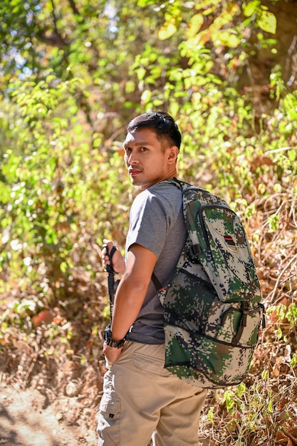 Retrato de um viajante asiático ativo com mochila e equipamento de trekking na floresta