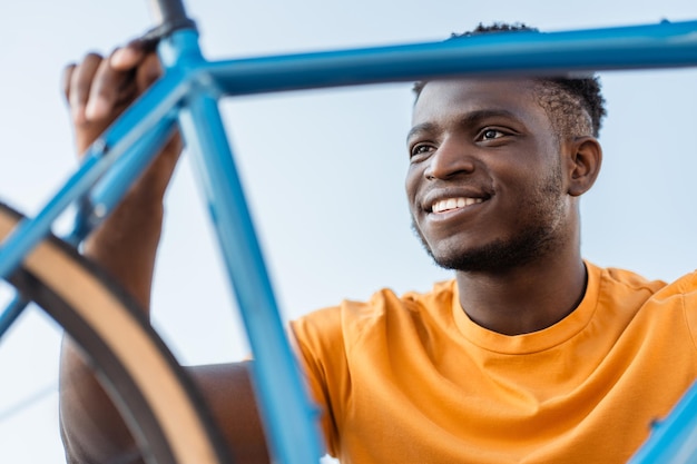 Retrato de um viajante bonito sorridente reparando uma bicicleta na rua