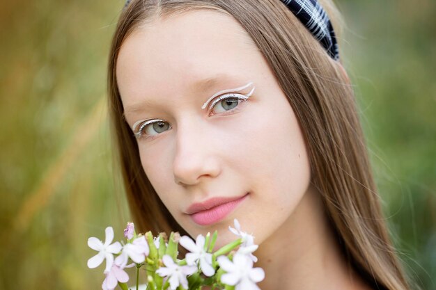 Retrato de uma adolescente com maquiagem coreana Linda garota loira segurando flores silvestres