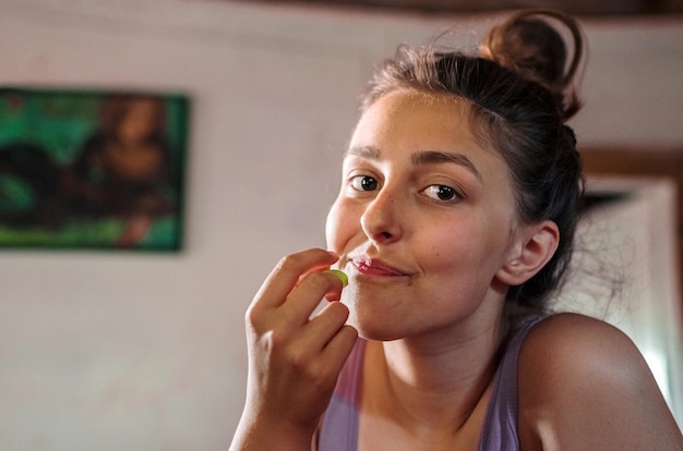 Foto retrato de uma adolescente comendo uva