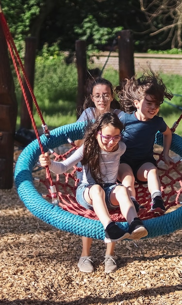 Retrato de uma adolescente empurrando suas irmãs em um balanço de corda redonda no parque