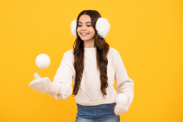 Retrato de uma adolescente engraçada em clima de inverno vestida com roupas quentes e luvas de malha brincam com bola de neve